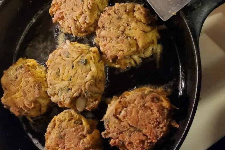 Golden-brown lions mane cakes frying in a black skillet, glistening with oil. The patties look crispy and homemade, evoking a warm, cozy feeling.
